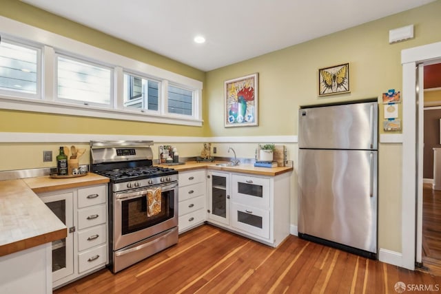 kitchen featuring white cabinetry, stainless steel appliances, and wood counters