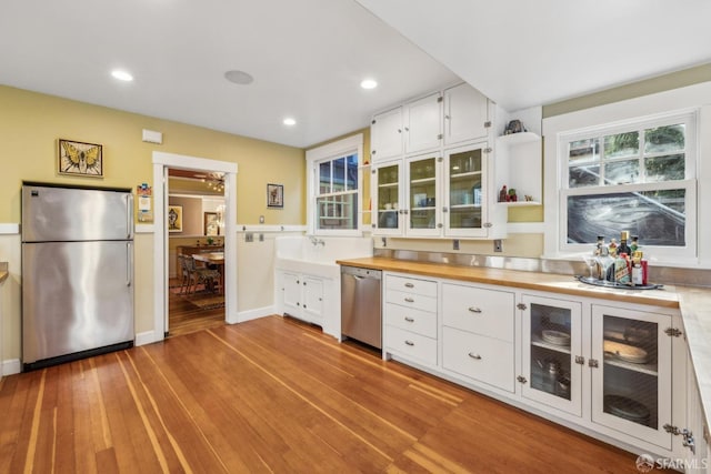 kitchen featuring white cabinets, glass insert cabinets, appliances with stainless steel finishes, wood counters, and light wood-type flooring