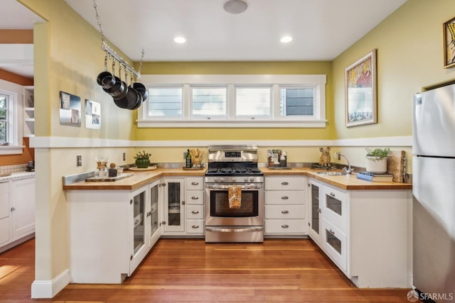 kitchen featuring white cabinets, light wood finished floors, appliances with stainless steel finishes, and wood counters