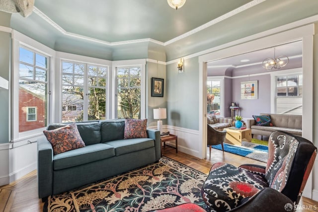 living room featuring a wealth of natural light, a wainscoted wall, wood finished floors, and ornamental molding