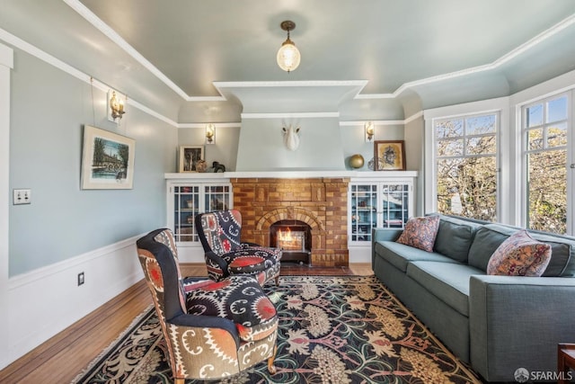 living room with a fireplace, crown molding, wood finished floors, and a wainscoted wall