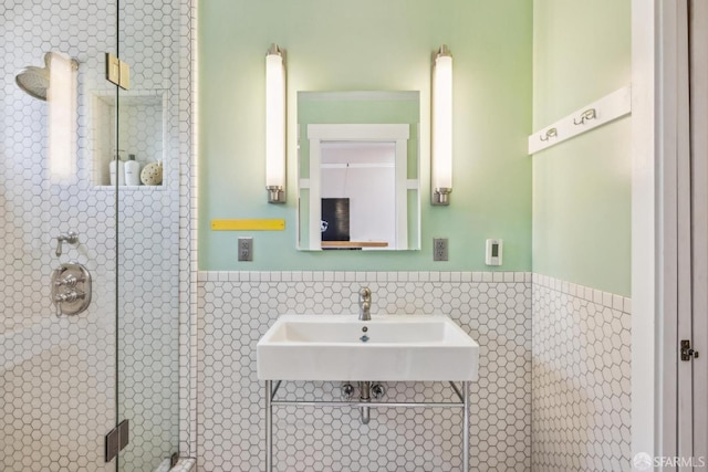 full bathroom featuring a wainscoted wall, a stall shower, and a sink