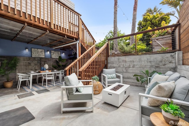 view of patio / terrace featuring stairs, an outdoor living space with a fire pit, a fenced backyard, and outdoor dining space