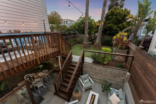 deck at dusk with stairway, a fenced backyard, and a patio