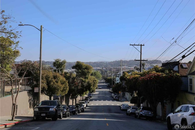 view of asphalt road with street lights, curbs, and sidewalks