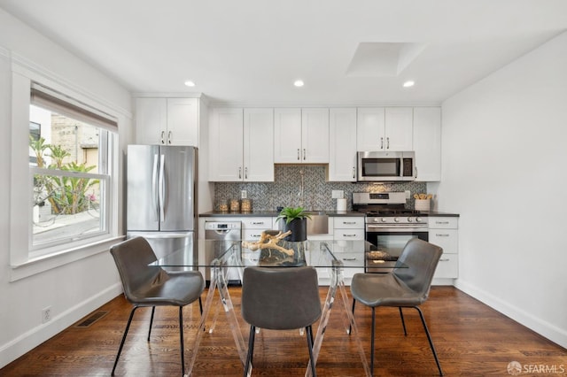 kitchen with appliances with stainless steel finishes, dark countertops, decorative backsplash, baseboards, and recessed lighting