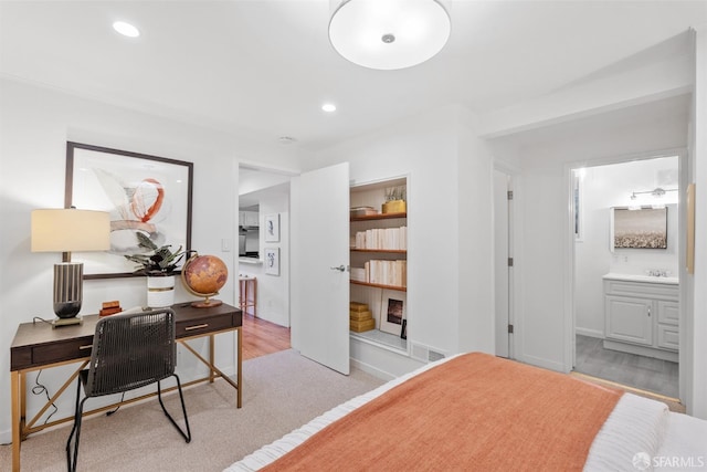 bedroom with connected bathroom and light carpet