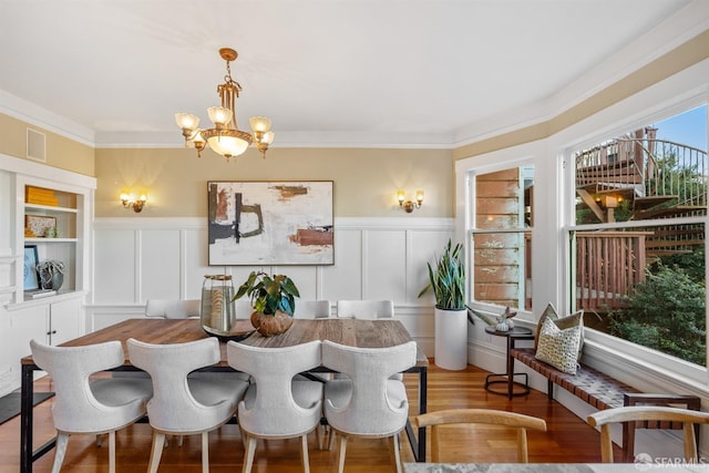 dining space with ornamental molding, an inviting chandelier, and light hardwood / wood-style floors