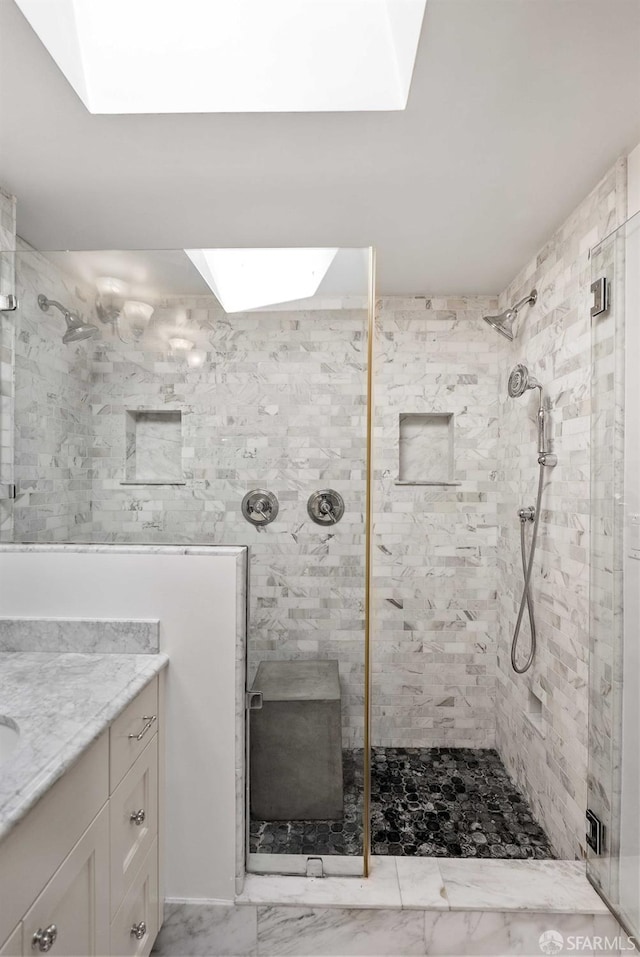 bathroom featuring vanity, a skylight, and a tile shower