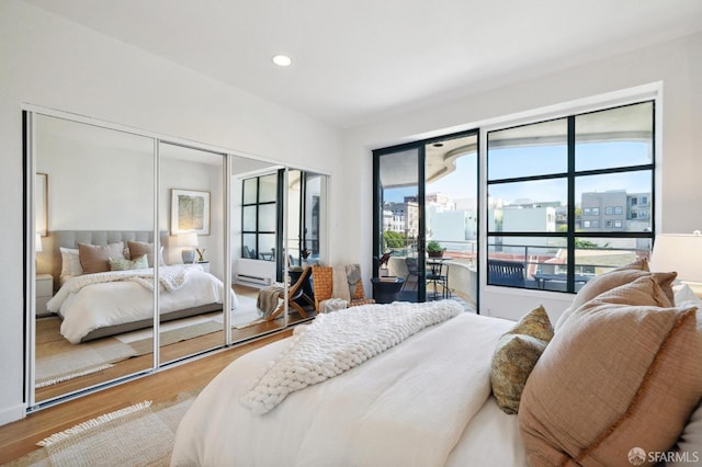 bedroom with hardwood / wood-style floors, multiple windows, and access to exterior