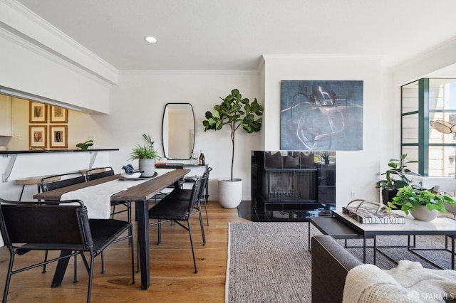 dining space with ornamental molding, hardwood / wood-style floors, and a fireplace