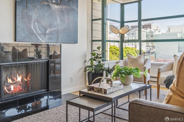 living room with baseboard heating, a tiled fireplace, and a healthy amount of sunlight