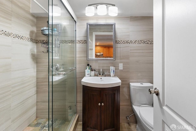 bathroom with toilet, tile walls, an enclosed shower, and vanity