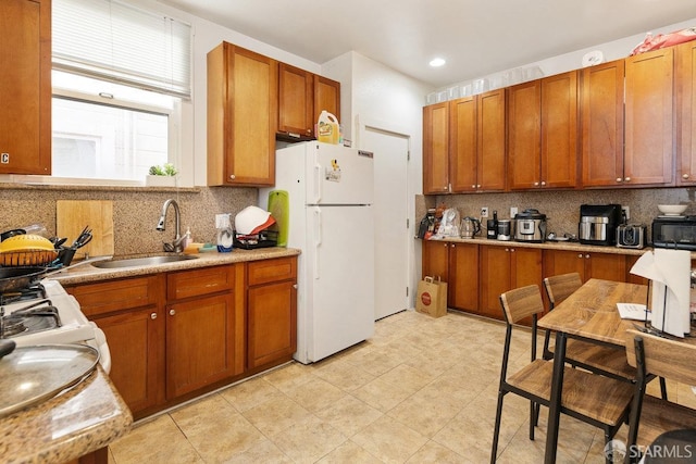 kitchen featuring white fridge, backsplash, and sink