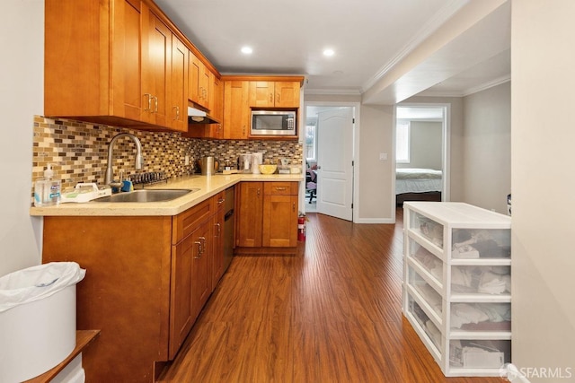 kitchen with stainless steel microwave, backsplash, wood-type flooring, sink, and crown molding