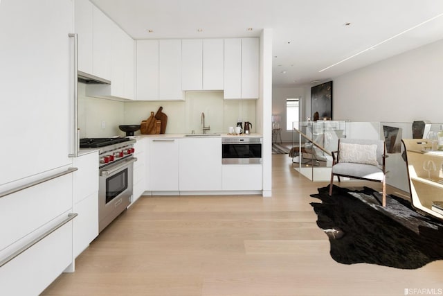 kitchen with appliances with stainless steel finishes, light hardwood / wood-style flooring, and white cabinetry