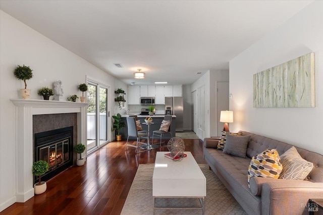 living area featuring visible vents, wood finished floors, and a glass covered fireplace