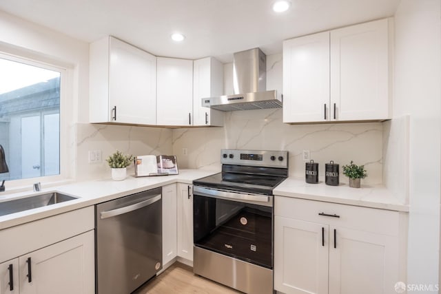 kitchen featuring sink, white cabinetry, stainless steel appliances, tasteful backsplash, and wall chimney exhaust hood