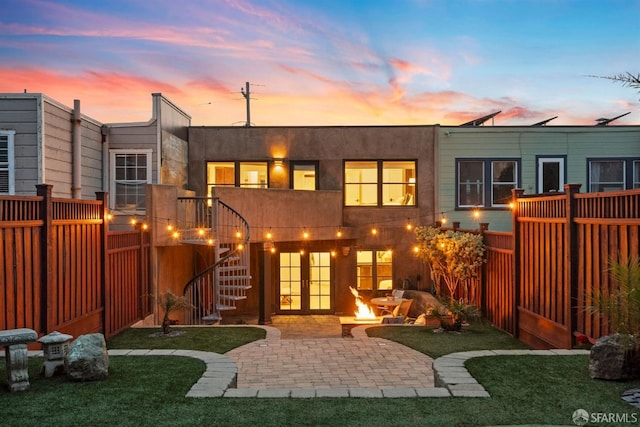 back of property at dusk with stairway, a patio, fence private yard, and stucco siding