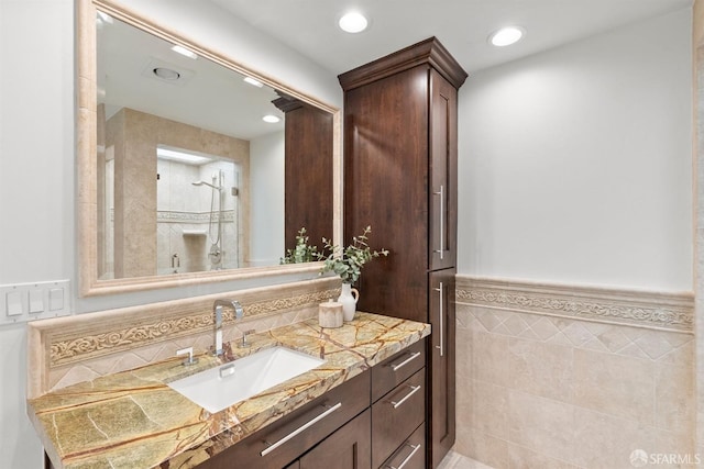 full bathroom with recessed lighting, tile walls, wainscoting, walk in shower, and vanity