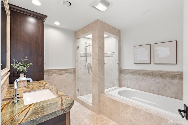 bathroom with vanity, recessed lighting, a stall shower, a garden tub, and tile walls