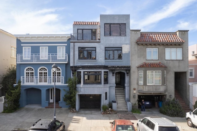 view of front of house with concrete driveway, stairway, a tile roof, and stucco siding