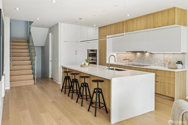 kitchen featuring white cabinetry, sink, a kitchen bar, stainless steel double oven, and black electric cooktop