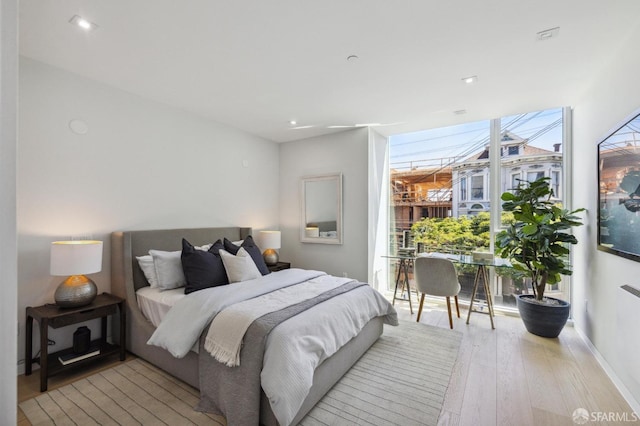 bedroom featuring expansive windows and light hardwood / wood-style flooring