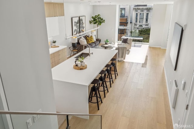 kitchen featuring light hardwood / wood-style flooring, a breakfast bar area, and white cabinets