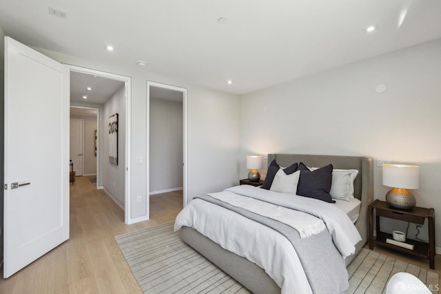 bedroom with a spacious closet and light hardwood / wood-style flooring