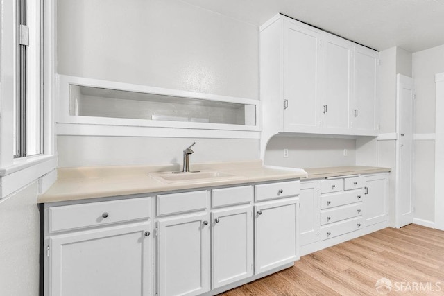 kitchen with sink, light hardwood / wood-style floors, and white cabinets