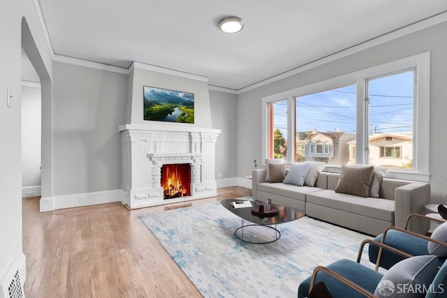 living room with a brick fireplace, crown molding, and hardwood / wood-style flooring