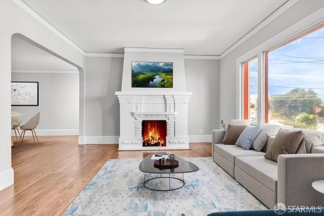 living room featuring a brick fireplace, hardwood / wood-style floors, and crown molding