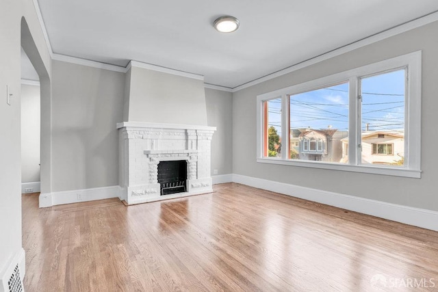 unfurnished living room featuring wood-type flooring, a brick fireplace, and ornamental molding