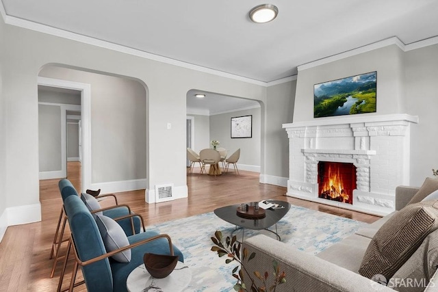 living room featuring crown molding, a fireplace, and hardwood / wood-style flooring