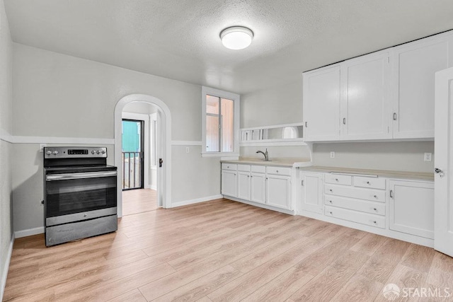 kitchen with a textured ceiling, stainless steel electric stove, light hardwood / wood-style floors, white cabinetry, and sink