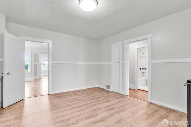 unfurnished room with a textured ceiling and light hardwood / wood-style floors