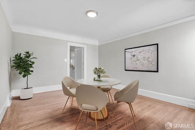 dining space with ornamental molding and hardwood / wood-style flooring