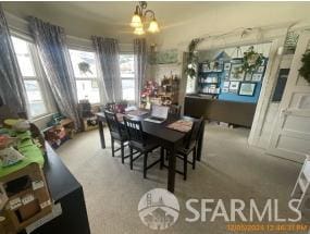 carpeted dining area with a chandelier