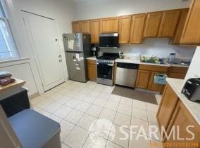 kitchen featuring appliances with stainless steel finishes, sink, and light tile patterned flooring