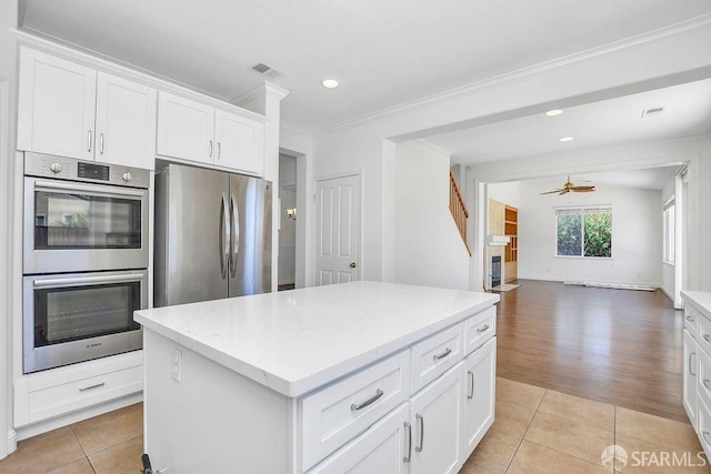 654 Tain Ct, Brentwood, CA 94513 - kitchen featuring appliances with stainless steel finishes, a kitchen island, ornamental molding, light tile patterned floors, and light stone counters