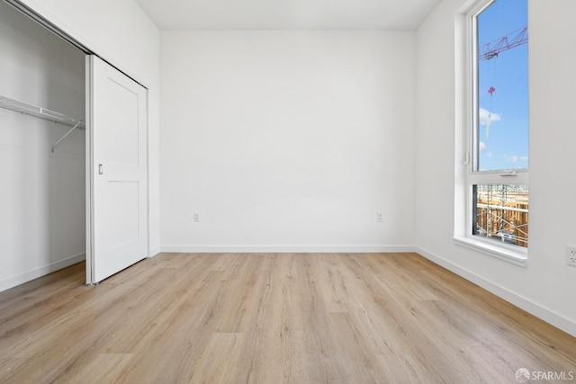 unfurnished bedroom with a closet and light wood-type flooring