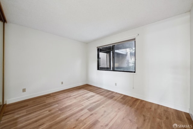 unfurnished room with a textured ceiling and wood-type flooring