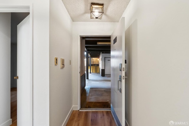 corridor featuring a textured ceiling and dark wood-type flooring