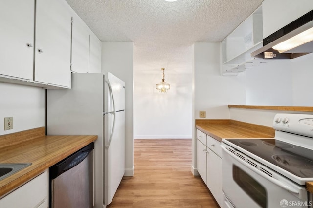 kitchen with white appliances, range hood, a textured ceiling, hanging light fixtures, and white cabinets