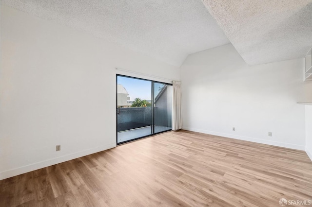 unfurnished room with a textured ceiling, light hardwood / wood-style flooring, and vaulted ceiling