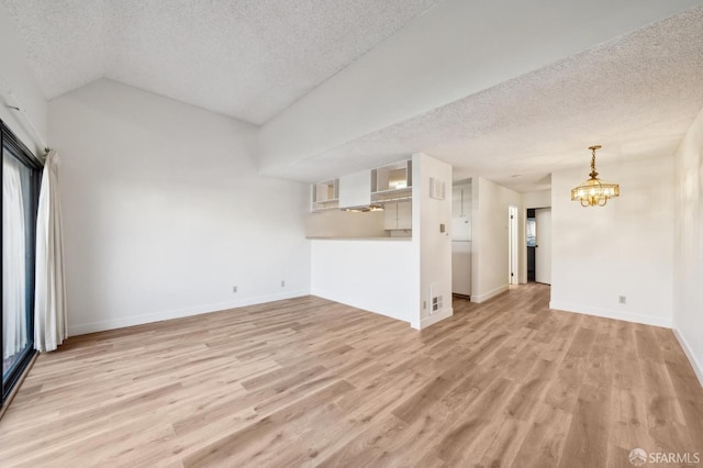 unfurnished living room featuring a textured ceiling, light hardwood / wood-style floors, an inviting chandelier, and lofted ceiling