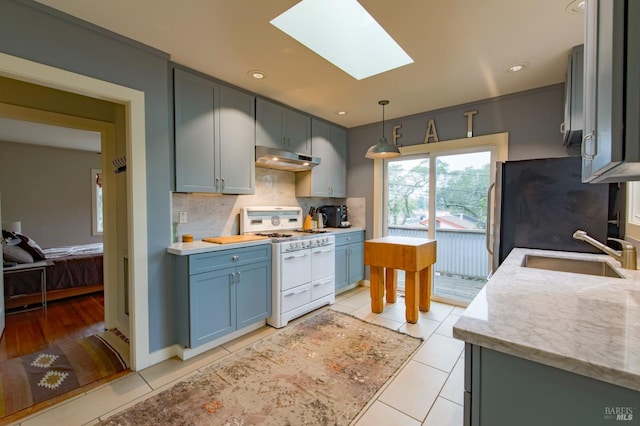 kitchen with a skylight, light tile patterned floors, sink, double oven range, and stainless steel fridge