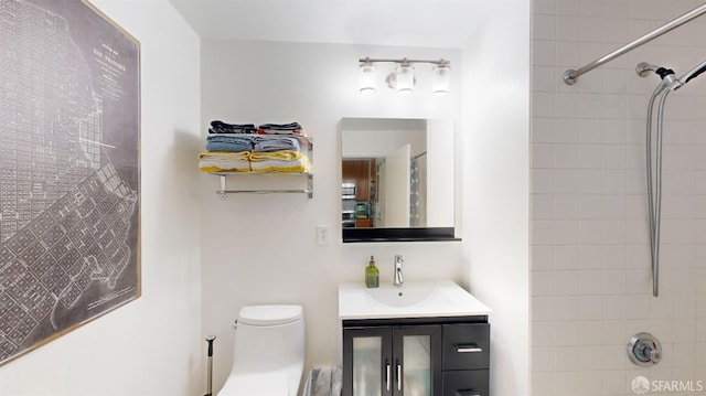 bathroom with tiled shower, vanity, and toilet