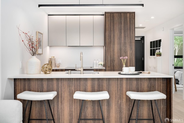 kitchen with a breakfast bar area, white cabinetry, and sink